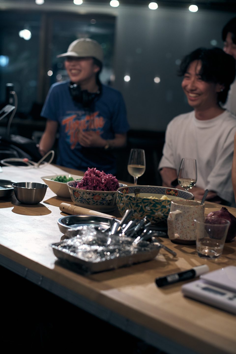 料理の並ぶカウンターと談笑するゲスト